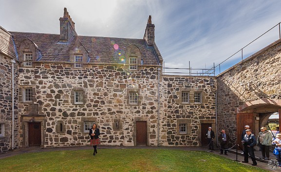 IsleOfMull2024-033 Our docent sporting Maclean tartan in the castle courtyard. If you look at the entrance you can get a sense of the 23 foot thick walls facing the land approach....