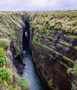 Orkney2024-014 The Gloup is an old sea cave whose roof has collapsed. There is a sea arch and blow hole on the seaward end and an 80 ft waterfall on the other.