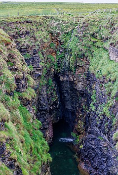 Orkney2024-016 The Gloup is an old sea cave whose roof has collapsed. There is a sea arch and blow hole on the seaward end and an 80 ft waterfall on the other.